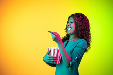 Image showing African-american young woman\'s portrait isolated on gradient yellow-green background in neon light