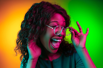 Image showing African-american young woman\'s portrait isolated on gradient yellow-green background in neon light