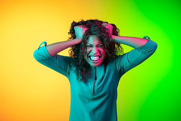 Image showing African-american young woman\'s portrait isolated on gradient yellow-green background in neon light