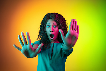 Image showing African-american young woman\'s portrait isolated on gradient yellow-green background in neon light