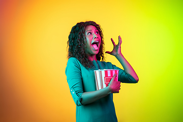 Image showing African-american young woman\'s portrait isolated on gradient yellow-green background in neon light