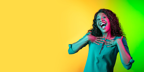 Image showing African-american young woman\'s portrait isolated on gradient yellow-green background in neon light