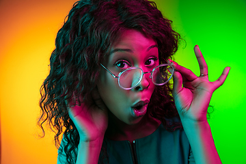 Image showing African-american young woman\'s portrait isolated on gradient yellow-green background in neon light