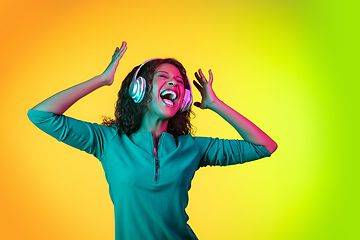 Image showing African-american young woman\'s portrait isolated on gradient yellow-green background in neon light