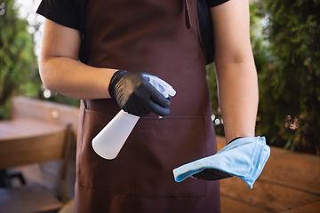 Image showing The waiter works in a restaurant in a medical mask, gloves during coronavirus pandemic