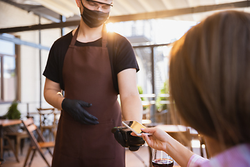 Image showing The waiter works in a restaurant in a medical mask, gloves during coronavirus pandemic