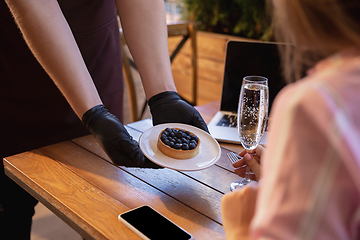 Image showing The waiter works in a restaurant in a medical mask, gloves during coronavirus pandemic