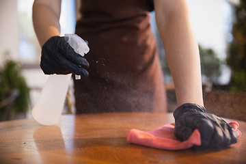 Image showing The waitress works in a restaurant in a medical mask, gloves during coronavirus pandemic