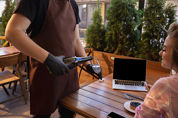 Image showing The waiter works in a restaurant in a medical mask, gloves during coronavirus pandemic