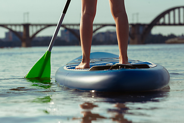 Image showing Young attractive woman standing on paddle board, SUP. Active life, sport, leisure activity concept