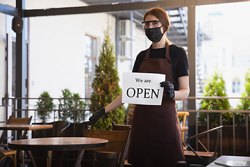 Image showing The waitress works in a restaurant in a medical mask, gloves during coronavirus pandemic