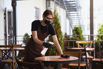 Image showing The waitress works in a restaurant in a medical mask, gloves during coronavirus pandemic