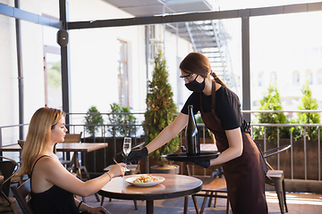 Image showing The waitress works in a restaurant in a medical mask, gloves during coronavirus pandemic