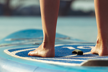 Image showing Young attractive woman standing on paddle board, SUP. Active life, sport, leisure activity concept