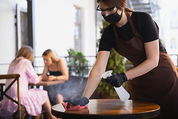 Image showing The waitress works in a restaurant in a medical mask, gloves during coronavirus pandemic