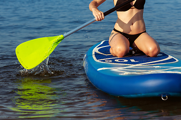 Image showing Young attractive woman sitting on paddle board, SUP. Active life, sport, leisure activity concept
