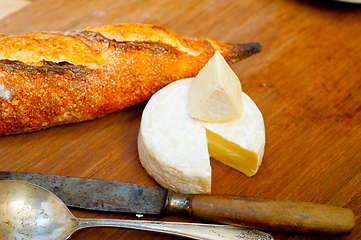 Image showing French cheese and fresh  baguette on a wood cutter