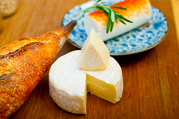 Image showing French cheese and fresh  baguette on a wood cutter