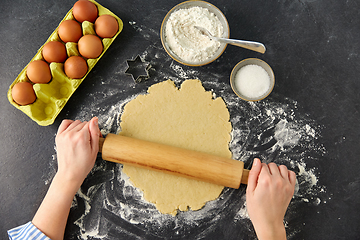 Image showing hands with rolling pin rolling dough on table