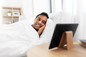 Image showing indian man looking at tablet pc in bed at home