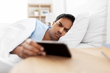 Image showing sleepy indian man with smartphone lying in bed