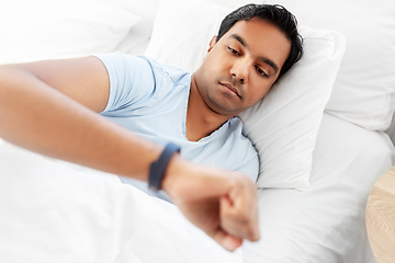 Image showing indian man with health tracker in bed at home