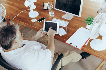 Image showing Businessman, manager in office with computer and fan cooling off, feeling hot, flushed