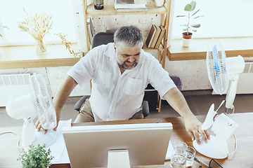 Image showing Businessman, manager in office with computer and fan cooling off, feeling hot, flushed