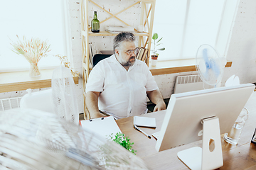Image showing Businessman, manager in office with computer and fan cooling off, feeling hot, flushed