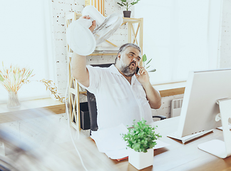 Image showing Businessman, manager in office with computer and fan cooling off, feeling hot, flushed