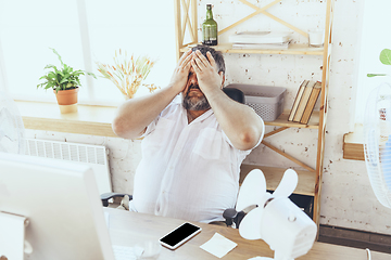 Image showing Businessman, manager in office with computer and fan cooling off, feeling hot, flushed