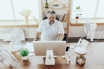 Image showing Businessman, manager in office with computer and fan cooling off, feeling hot, flushed