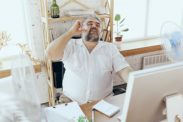 Image showing Businessman, manager in office with computer and fan cooling off, feeling hot, flushed