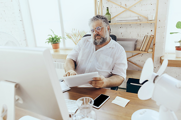 Image showing Businessman, manager in office with computer and fan cooling off, feeling hot, flushed