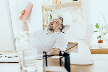 Image showing Businessman, manager in office with computer and fan cooling off, feeling hot, flushed