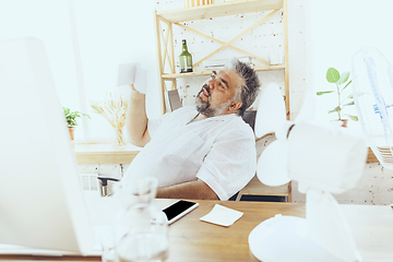 Image showing Businessman, manager in office with computer and fan cooling off, feeling hot, flushed