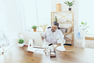 Image showing Businessman, manager in office with computer and fan cooling off, feeling hot, flushed