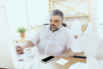 Image showing Businessman, manager in office with computer and fan cooling off, feeling hot, flushed