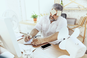 Image showing Businessman, manager in office with computer and fan cooling off, feeling hot, flushed