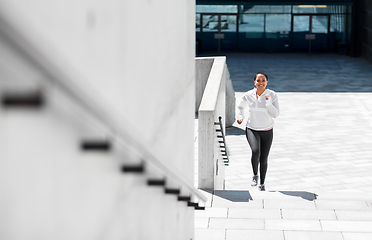 Image showing african american woman running upstairs outdoors