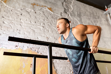 Image showing man doing triceps dip on parallel bars in gym