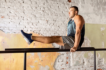 Image showing man flexing abs on parallel bars in gym