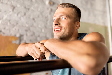 Image showing smiling young man at parallel bars in gym