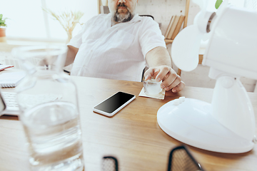 Image showing Businessman, manager in office with computer and fan cooling off, feeling hot, flushed