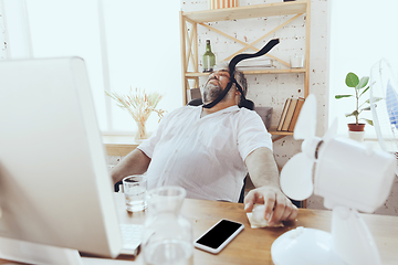 Image showing Businessman, manager in office with computer and fan cooling off, feeling hot, flushed