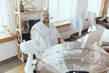 Image showing Businessman, manager in office with computer and fan cooling off, feeling hot, flushed