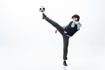 Image showing Man in office clothes playing football or soccer with ball on white background. Unusual look for businessman in motion, action. Sport, healthy lifestyle.