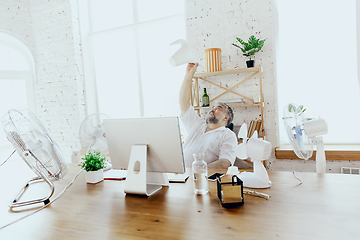 Image showing Businessman, manager in office with computer and fan cooling off, feeling hot, flushed