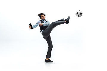 Image showing Man in office clothes playing football or soccer with ball on white background. Unusual look for businessman in motion, action. Sport, healthy lifestyle.