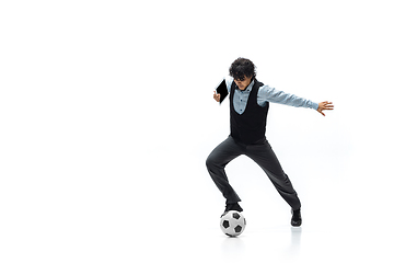 Image showing Man in office clothes playing football or soccer with ball on white background. Unusual look for businessman in motion, action. Sport, healthy lifestyle.